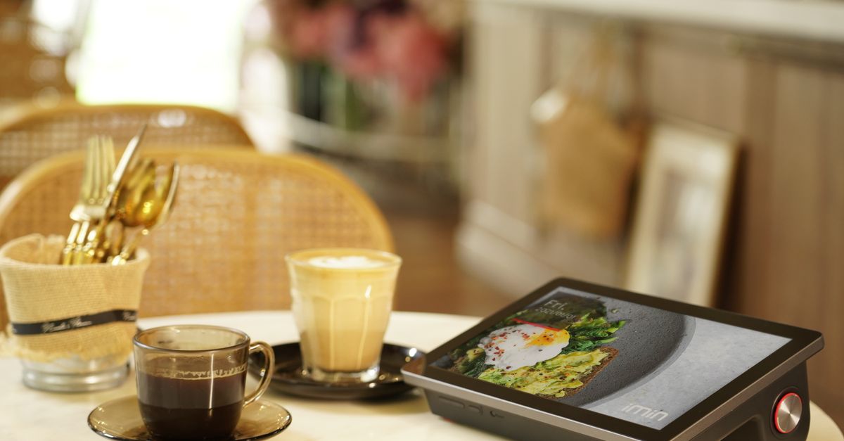 A cozy cafe setting featuring coffee cups and a digital menu tablet on a table.